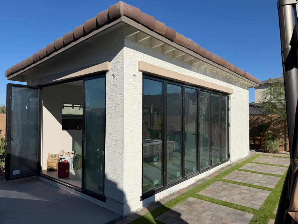 Fachada del Pool Lounge 325 con puertas plegables de cristal y patio de adoquín con pasto sintético