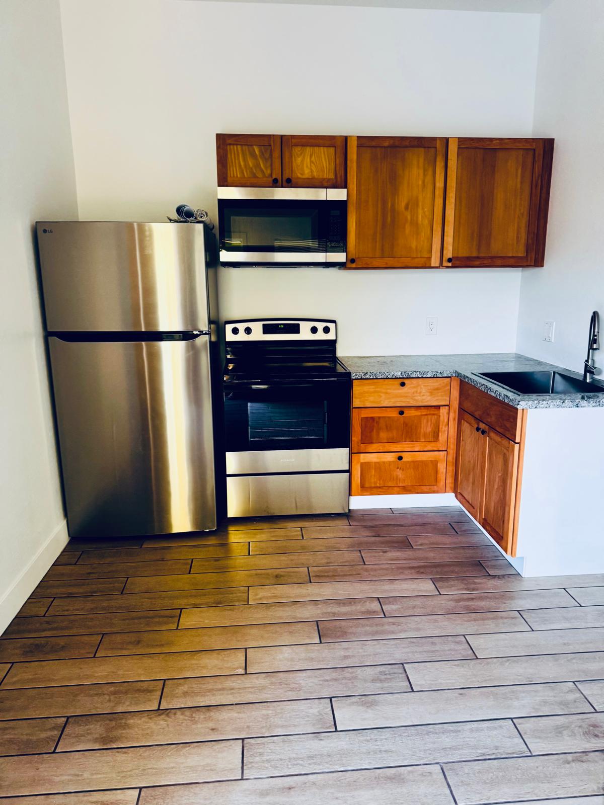 Cocina equipada con refrigerador, estufa, microondas y gabinetes de madera — Duplex 817