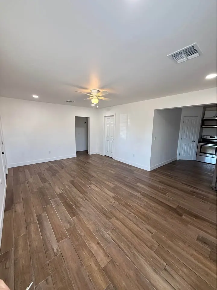 Sala amplia con piso tipo madera y ventilador de techo