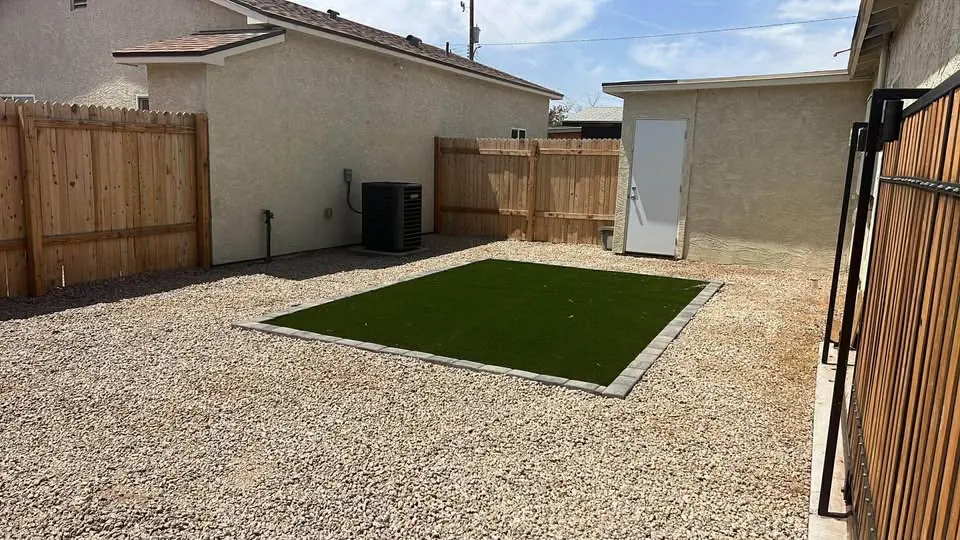 Patio trasero con grama sintética y cerca de madera