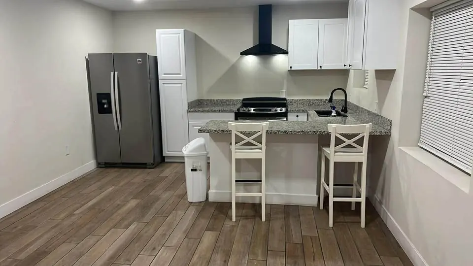 Cocina con isla, gabinetes blancos y granito