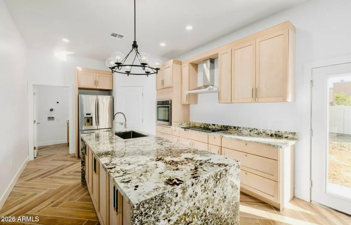 Cocina con isla de granito y gabinetes de madera natural