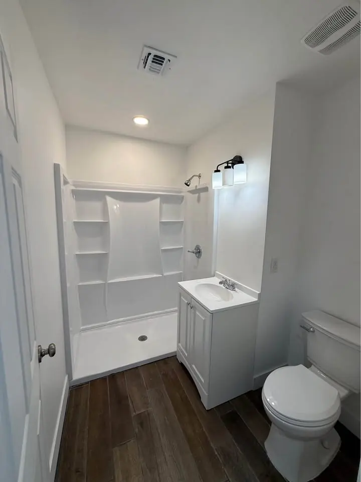 Baño completo con ducha, vanidad y piso tipo madera