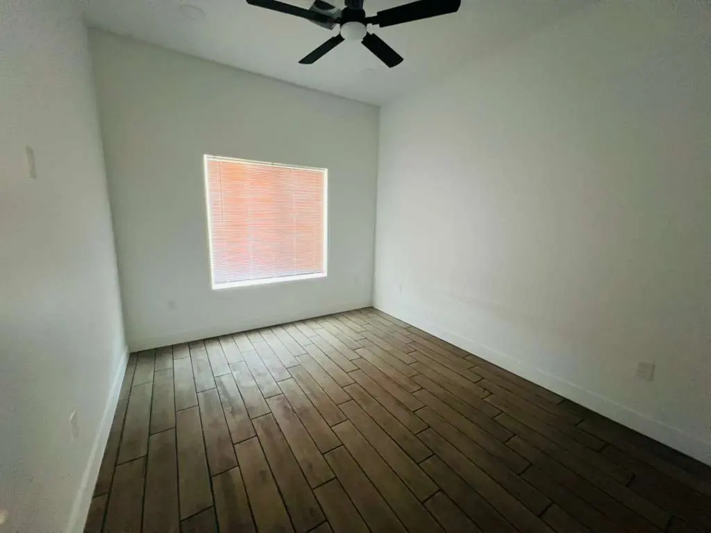 Recámara con piso tipo madera oscura y ventilador de techo
