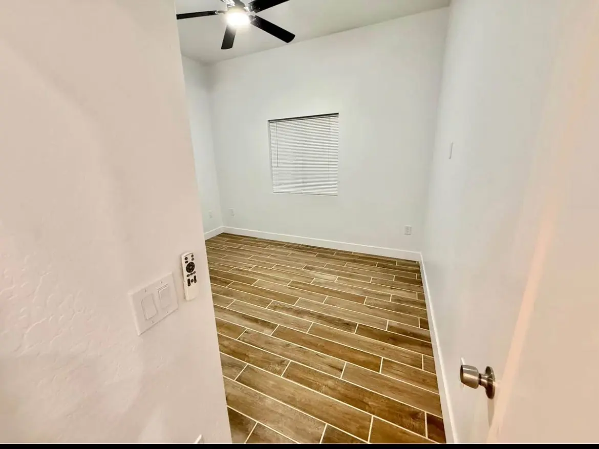 Recámara con ventilador de techo y piso tipo madera