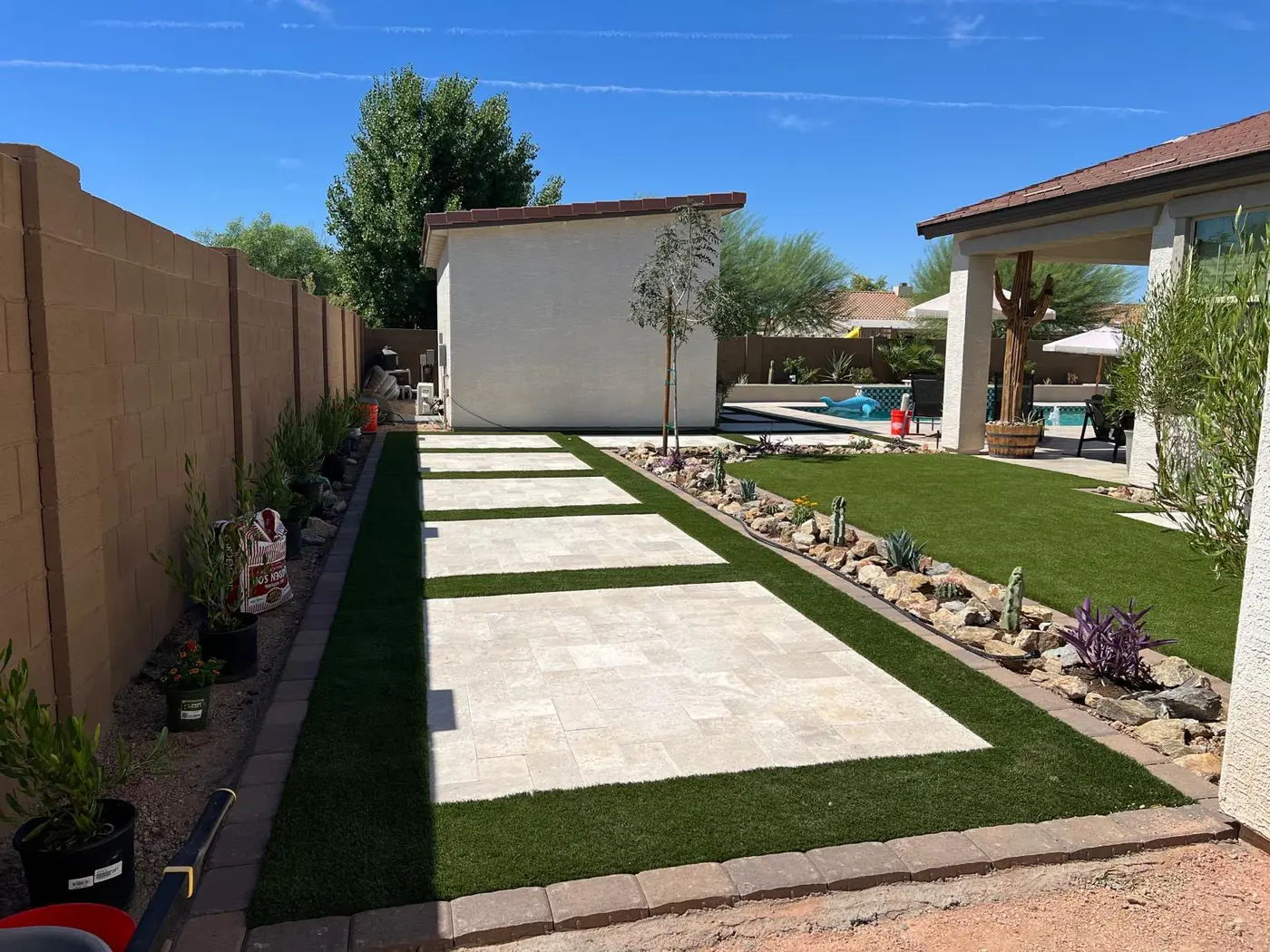 Andador de travertino con grama sintética hacia el Pool Lounge